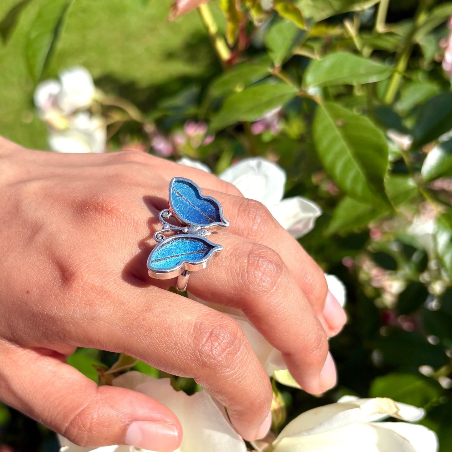 Bague papillon Azura portée à la main en lumière naturelle

