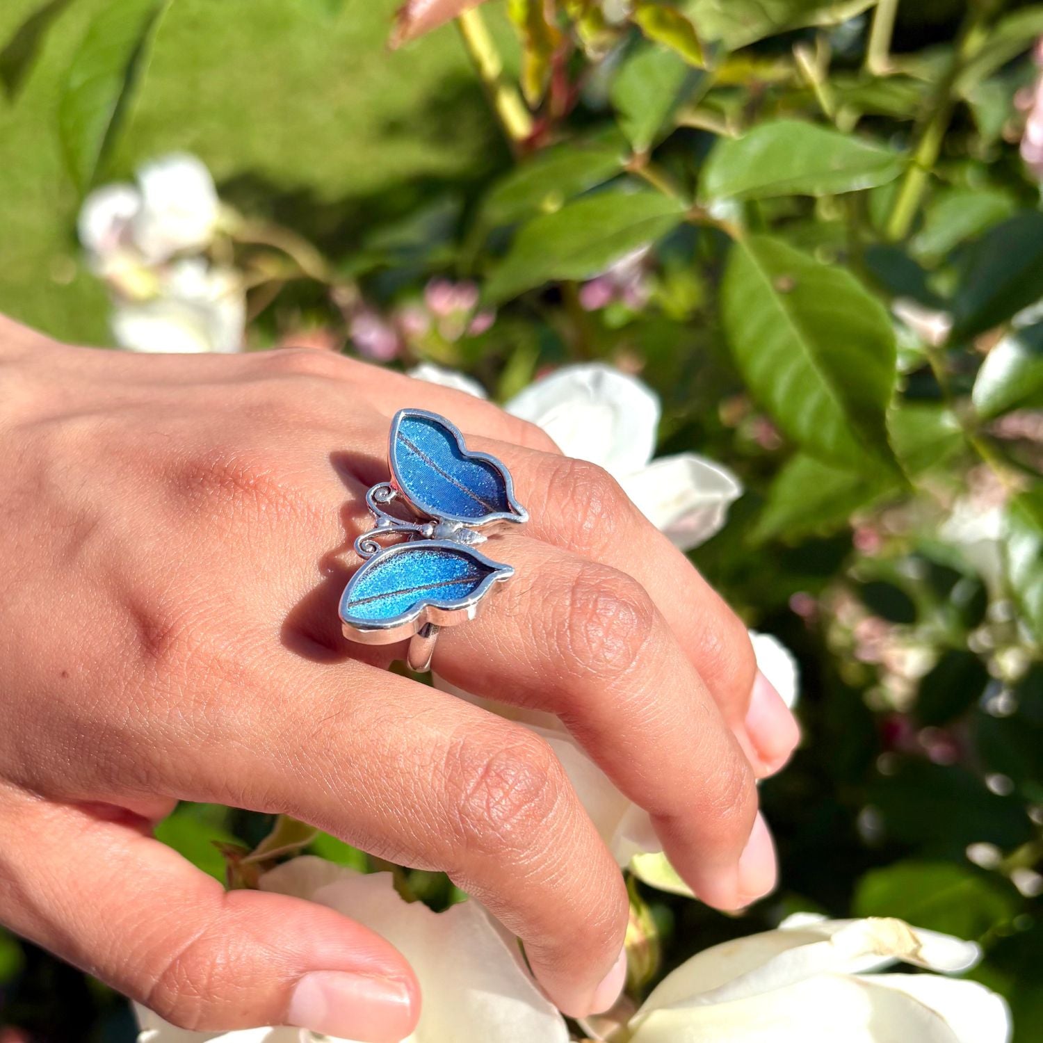 Bague papillon Azura portée à la main en lumière naturelle


