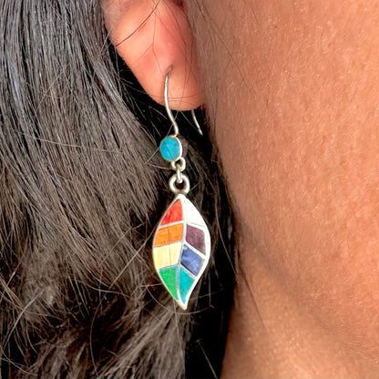Boucles d'oreilles Sylva portées de près révélant le motif feuille stylisée et les pierres naturelles multicolores