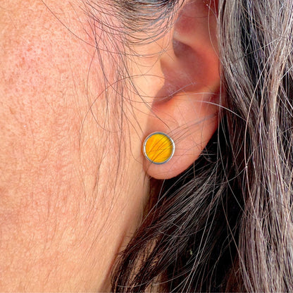 Boucles d'oreilles rondes jaune doré portées à l'oreille
