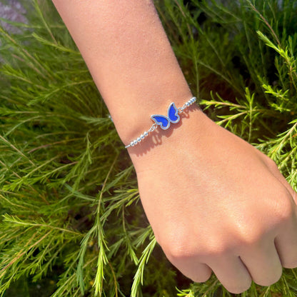 Bracelet Azuria porté au poignet avec papillon aux reflets bleus intenses.
