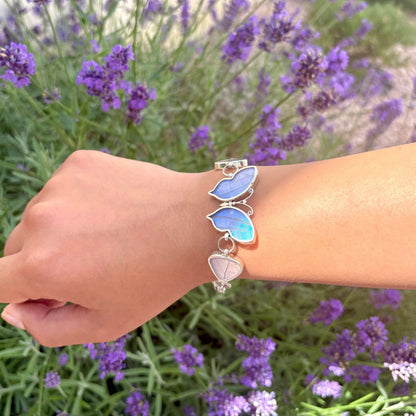 Bracelet Lumira porté au poignet avec papillon central et véritables ailes de papillon aux reflets bleu irisé 