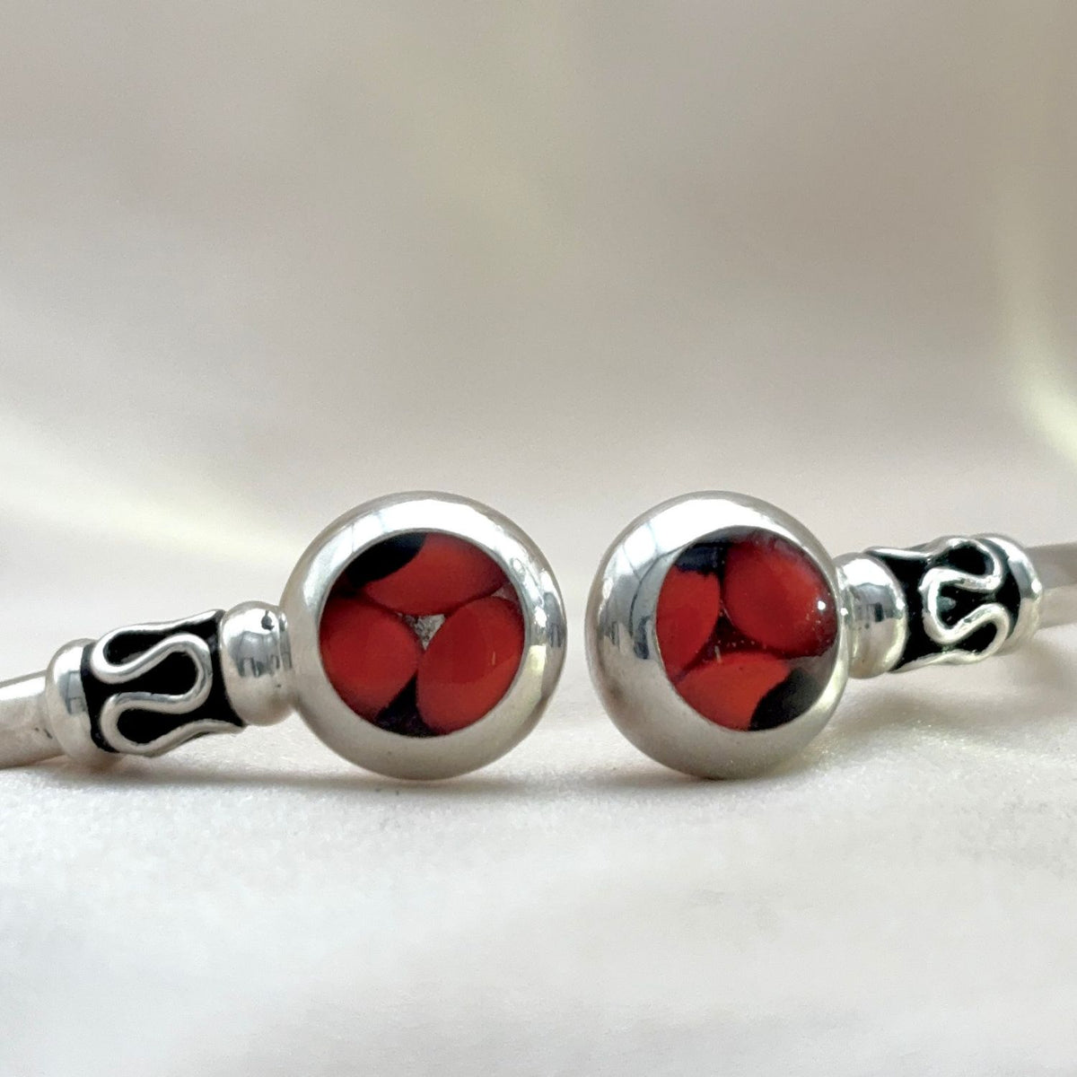 Détail des deux motifs en huayruro rouge et noir sur jonc en argent