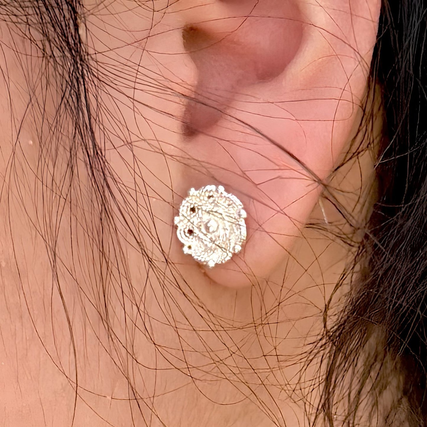 Gros plan sur les boucles d'oreilles Roséa portées, révélant la finesse du travail ajouré et les détails de fabrication artisanale. 