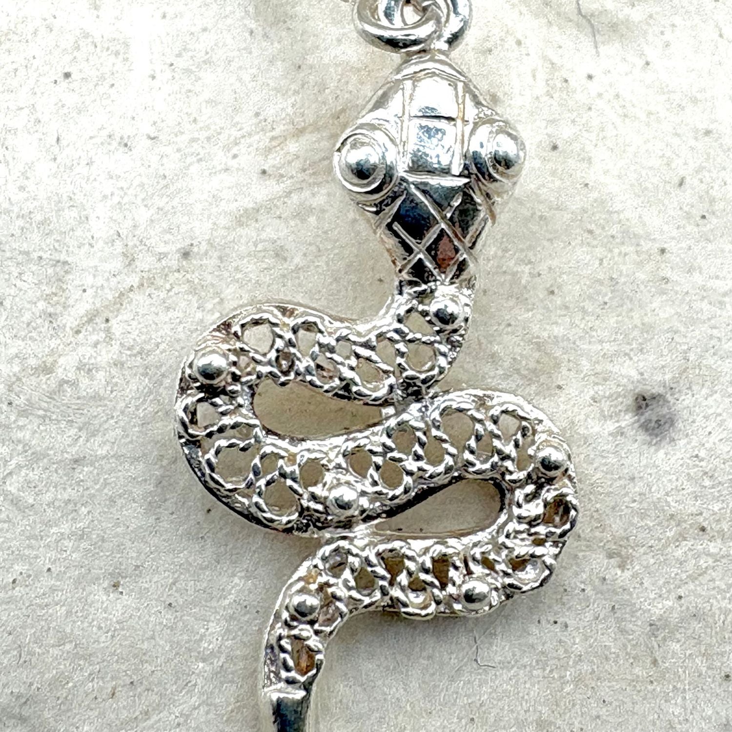 Gros plan sur une boucle d'oreille Ondine en argent  révélant le travail ajouré et les finitions artisanales.

