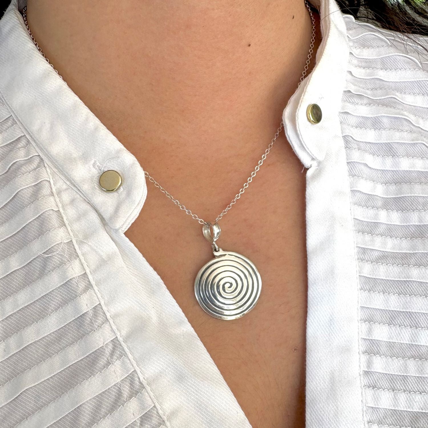 Pendentif Spira porté avec chaîne en argent, création artisanale inspirée de la spirale.