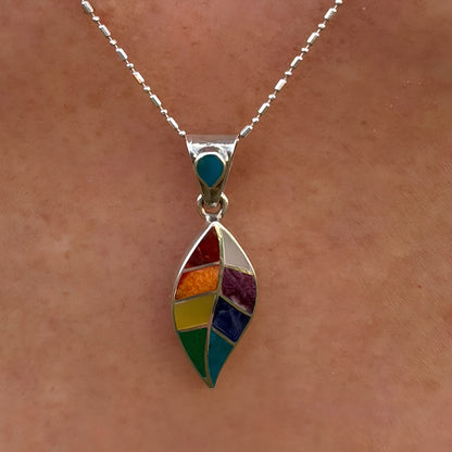 Pendentif Sylva porté de près avec motif feuille stylisée et pierres naturelles multicolores