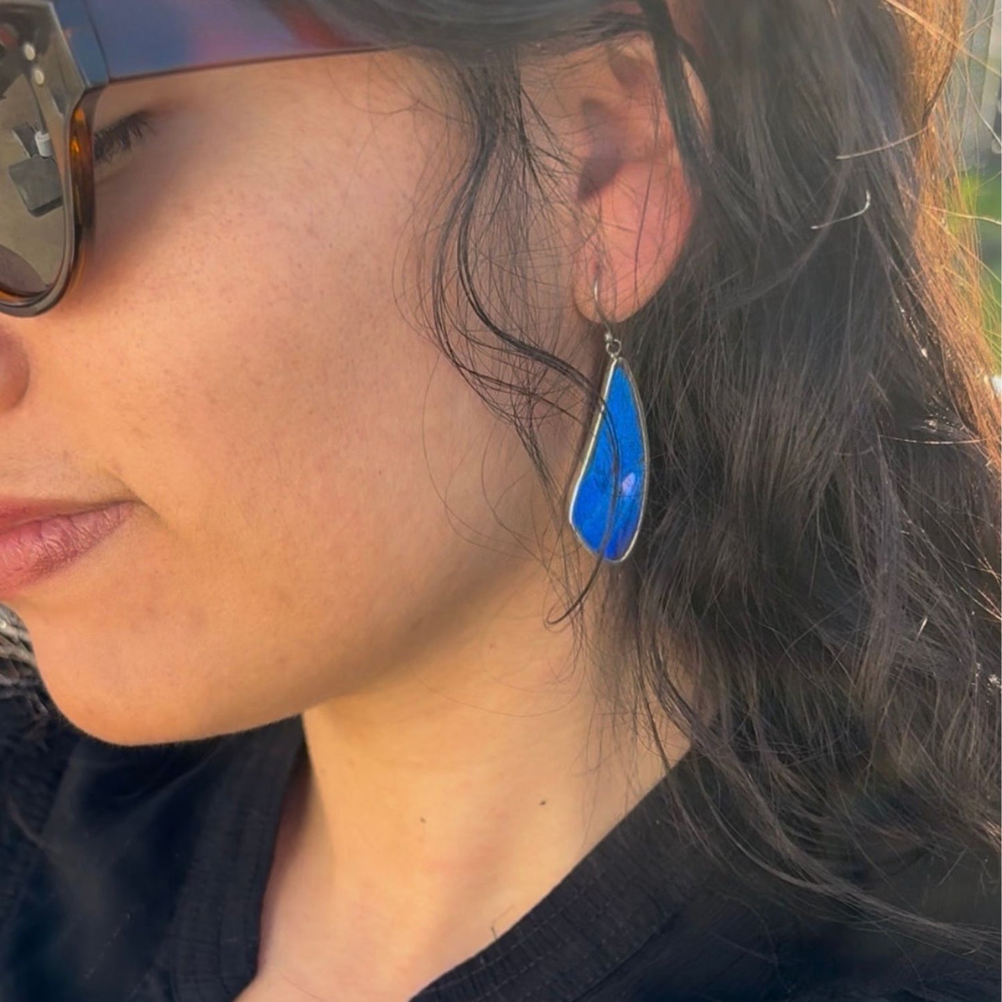 Boucles d'oreilles portées artisanales en argent et ailes de papillon bleu intense.