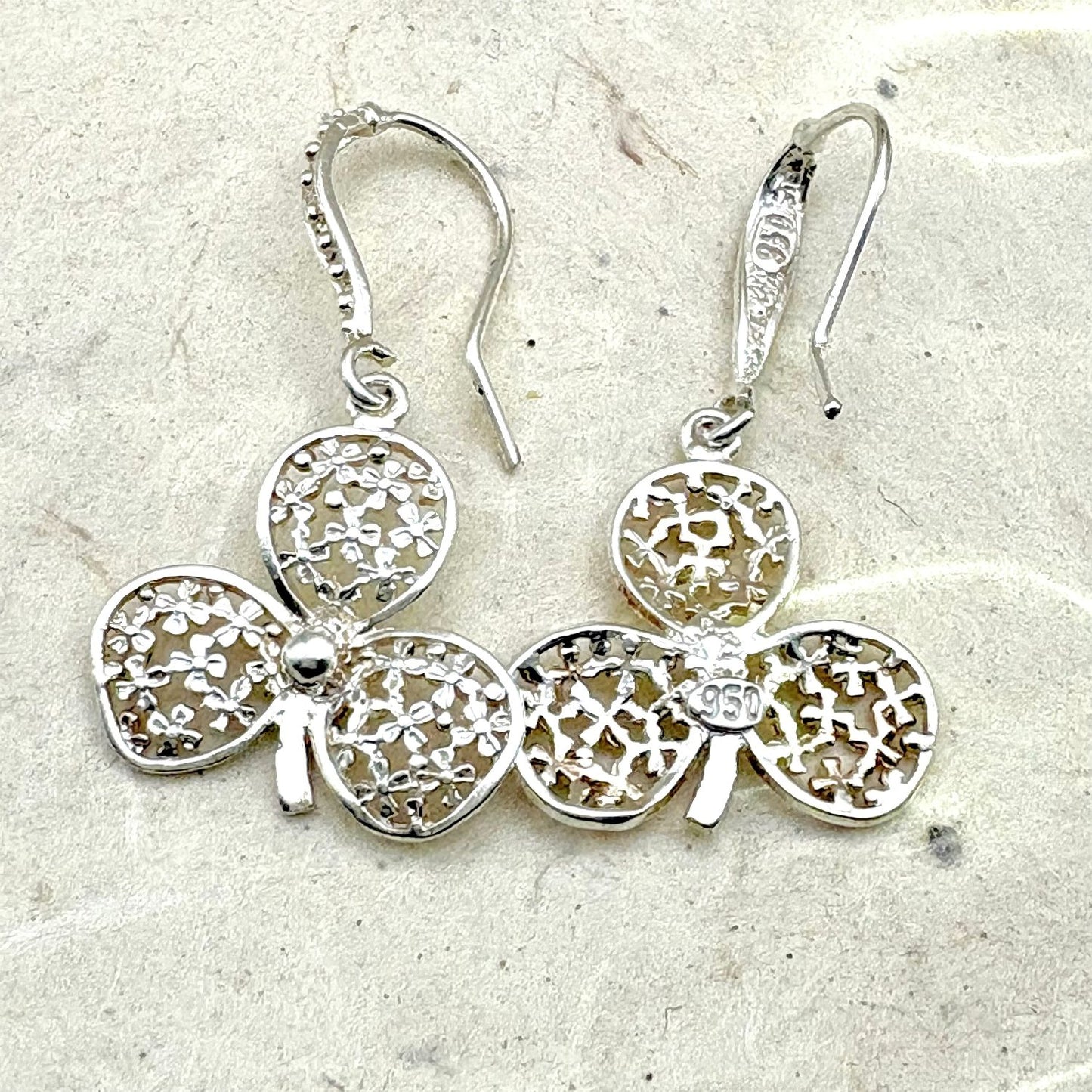 Vue avant et arrière des boucles d'oreilles Folia mettant en valeur les détails du travail artisanal et du fermoir.