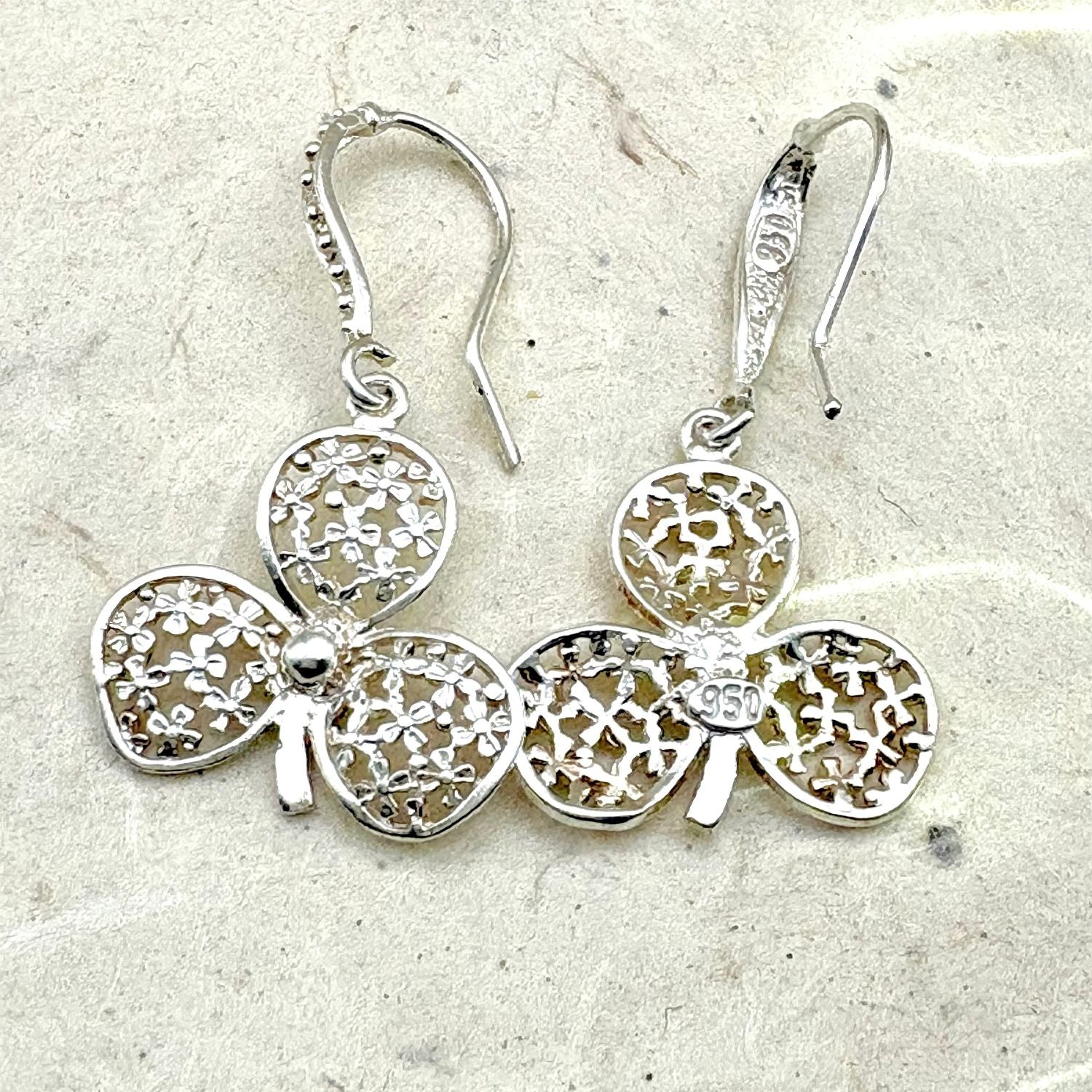 Vue avant et arrière des boucles d'oreilles Folia mettant en valeur les détails du travail artisanal et du fermoir.