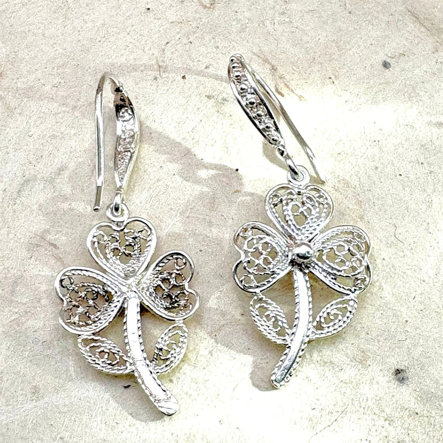 Vue avant et arrière des boucles d'oreilles Trèva mettant en valeur les détails du travail artisanal et du fermoir.