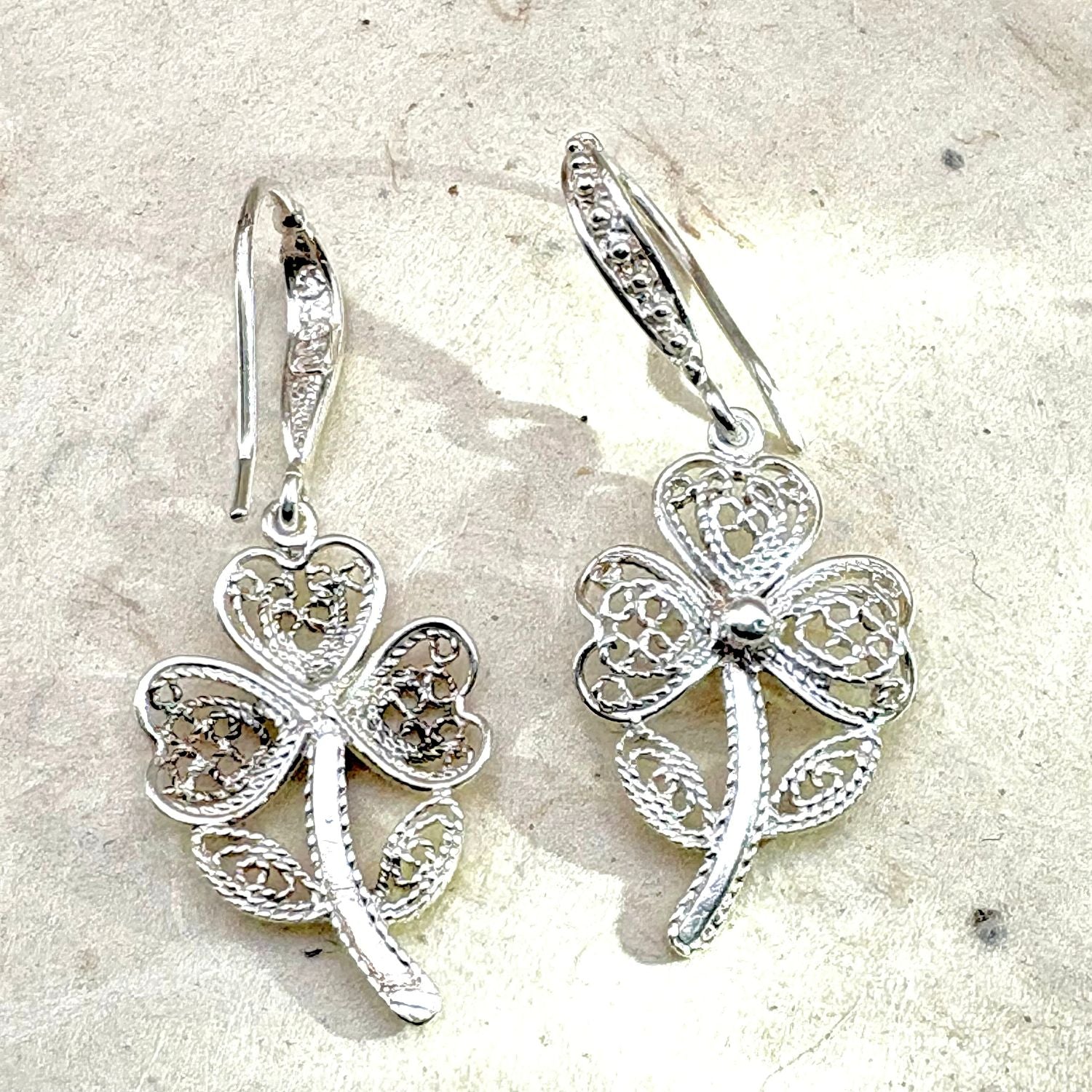 Vue avant et arrière des boucles d'oreilles Trèva mettant en valeur les détails du travail artisanal et du fermoir.