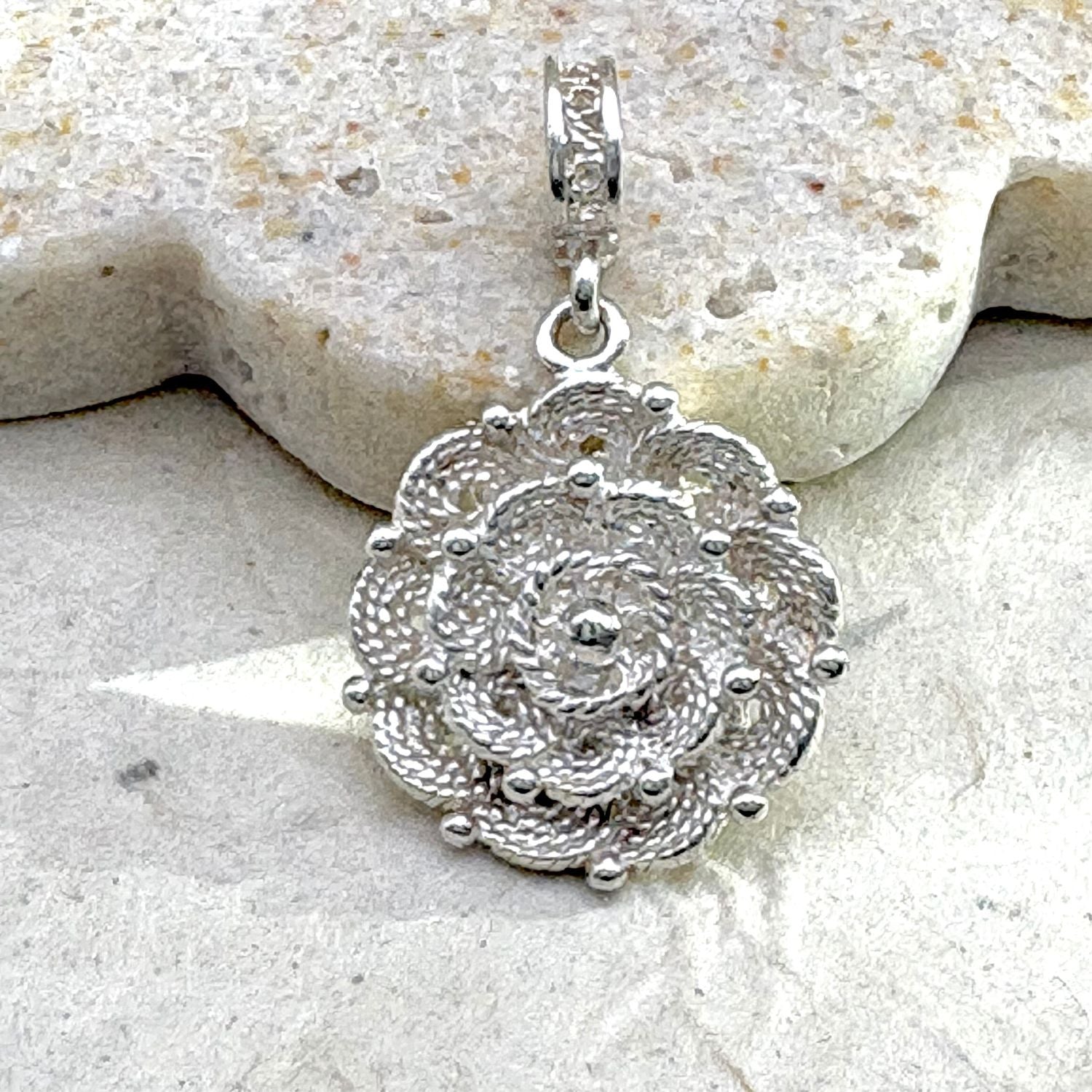 Vue rapprochée du pendentif Roséa révélant les détails du travail artisanal et les motifs aux reliefs 